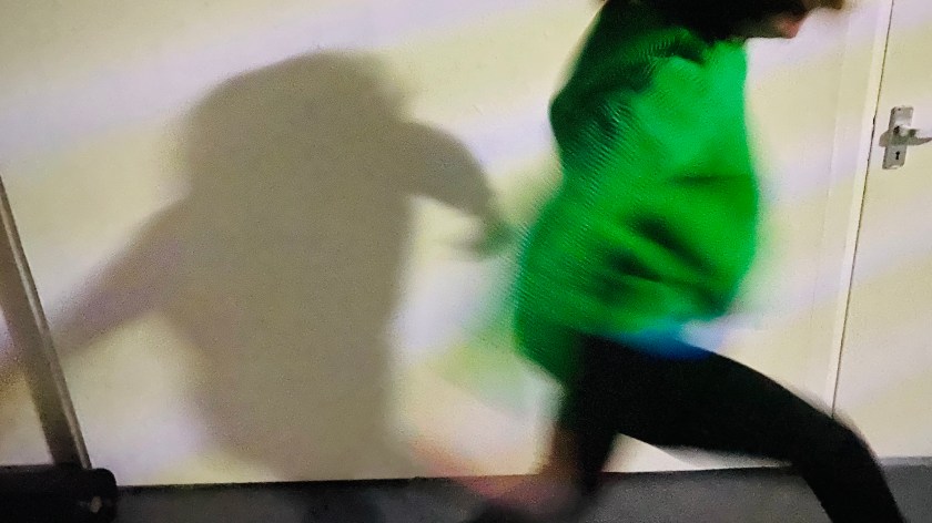 A woman runs around in a blur wearing a green jumper